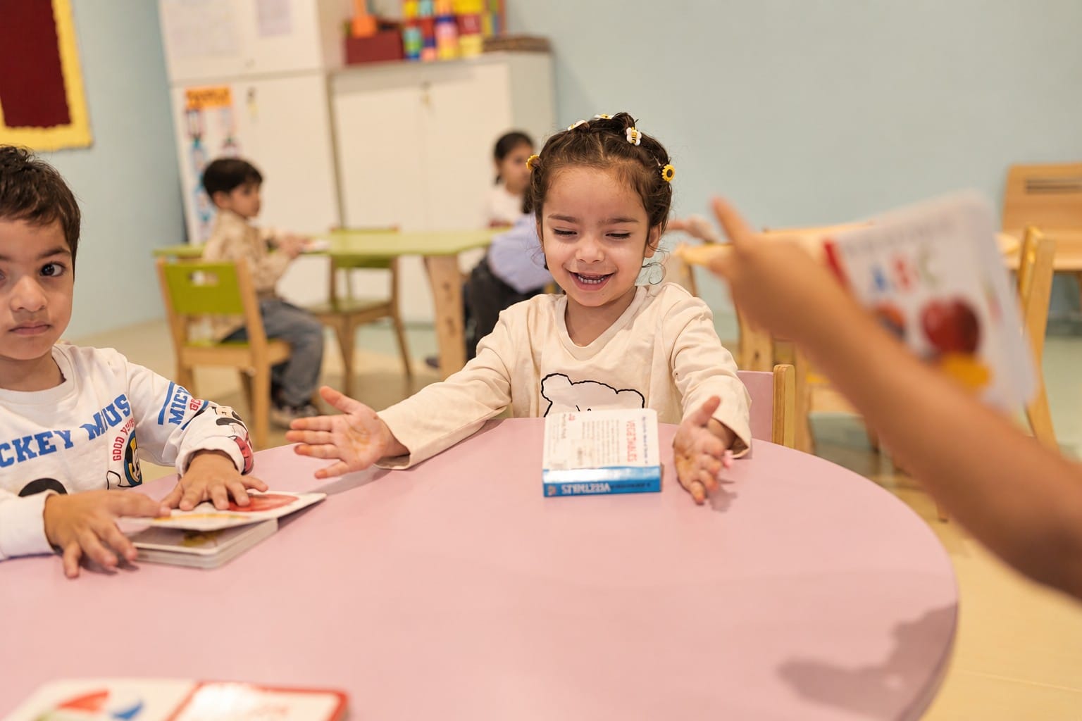 A girl holding out her picture card with a smile