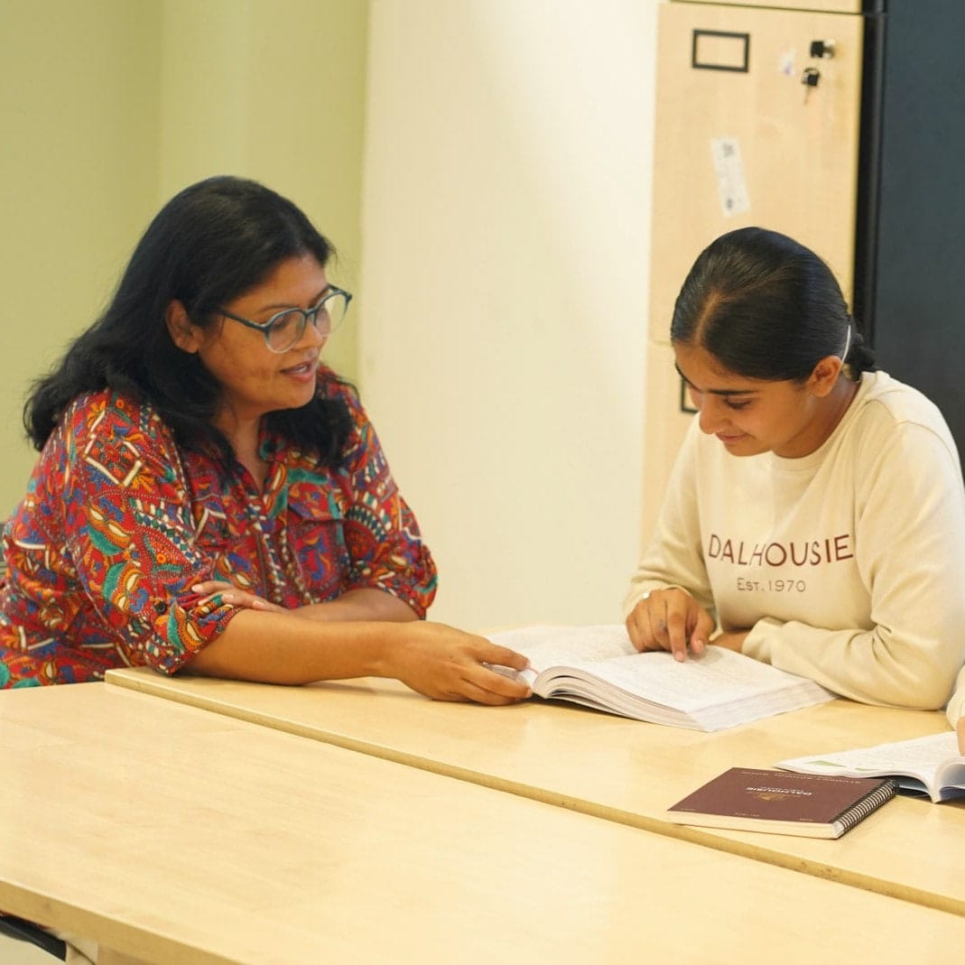 A teacher listening to a student at her desk
